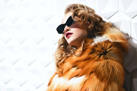 A portrait of a beautiful girl wearing a fur coat and sunglasses. Beauty, winter and spring fashion.の写真素材