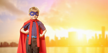 A portrait of a funny serious young boy posing in the costume of superhero. Kids development and...