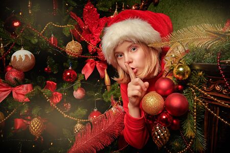 Funny mischievous girl hunts down Santa Claus, hiding behind a New Yearâs fireplace at home. Merry Christmas and Happy New Year!の写真素材