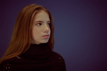 Portrait of a beautiful young girl with freckles on her face on a dark background. Studio portrait.の写真素材