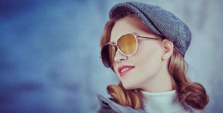 Romantic young woman with natural makeup and beautiful wavy blonde hair wearing autumn clothes and trendy glasses. Beauty, fashion concept. Optics and eyewear style.の写真素材
