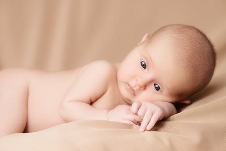 Portrait of a sweet newborn baby lying on a beige blanket. Baby care, Healthcare, pediatrics.