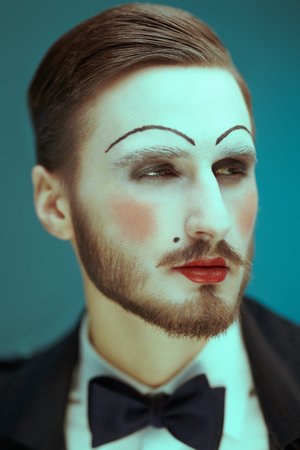 Art and fashion. Portrait of a young man with makeup in the style of the 20s in an elegant suit...