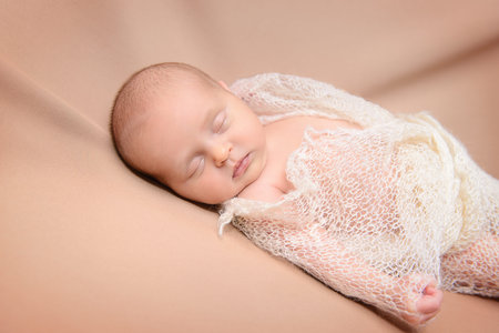 Portrait of a lovely sleeping newborn baby wrapped in knitted blanket. Baby care, Healthcare.