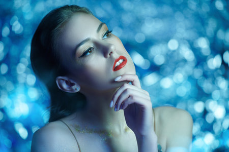 Make-up and cosmetics. Portrait of a gorgeous young woman with golden make-up on a sparkling silver...