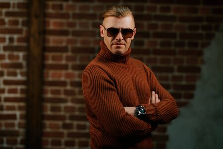 Handsome mature man in sunglasses over brick wall background. Optics style.の写真素材