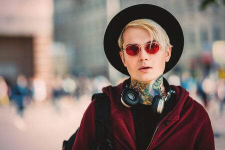 A portrait of a young fair-haired guy walking in the street. Beauty, optics, casual fashion.の写真素材