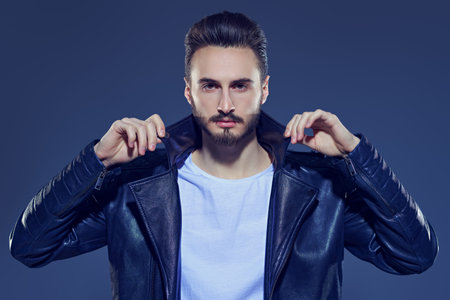 Men's fashion. Handsome man in casual white t-shirt and black leather jacket. Studio portrait.