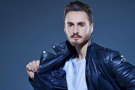 Men's fashion. Handsome man in casual white t-shirt and black leather jacket. Studio portrait.