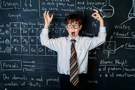 Excited schoolboy stands by a blackboard on a chemistry lesson. Educational concept.の写真素材