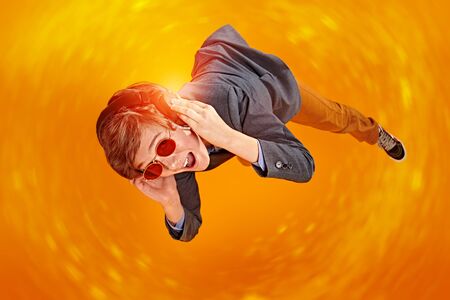 Happy emotional teen boy listening to music in headphones with joy. Studio shot on a yellow background. Copy space.の写真素材