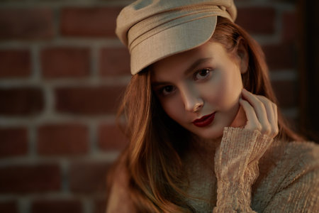 Close-up portrait of a pretty young girl with natural make-up and in a light beige dress and a cap...