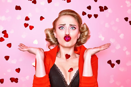 Love concept. Portrait of a pretty blonde woman with red heart on her lips on a pink background. Valentine's Day.の写真素材