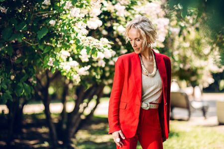 A portrait of an elderly stylish woman in a blooming Park. Beauty, fashion.の写真素材