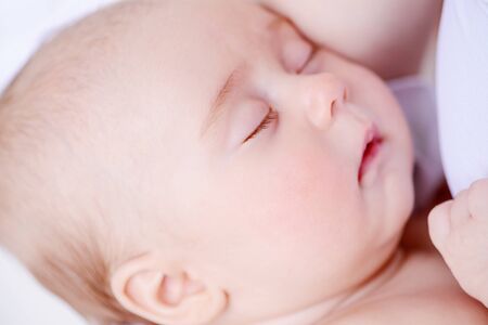 Close-up portrait of a sweet baby sleeping on mom's hands. Baby care. Healthcare.の写真素材