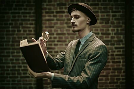 Detective man looking intently through a magnifying glass. Retro style. Occupation, criminal world.の写真素材