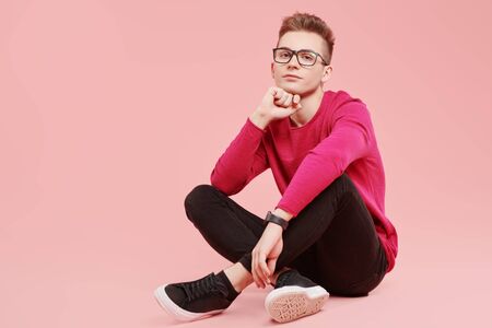 Youth fashion. Elegant young man in modern clothes posing on a pink background.の写真素材