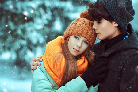 Couple of happy romantic young people hugging in a winter park and smiling. Winter season.