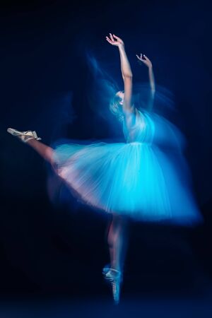 A full length portrait of a refined female ballet dancer posing in the studio over the dark blue background. Talent, fashion for ballet dancers. の写真素材