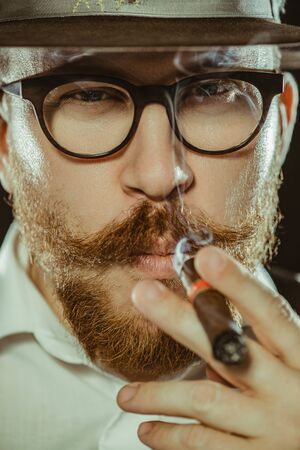 A close up portrait of a man smoking  a cigar. Men's beauty, fashion, style.の写真素材