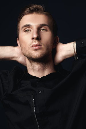 Men's beauty, fashion. Portrait of a handsome young man posing at studio on a dark blue background.