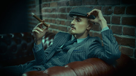 Portrait of a handsome courageous man sitting pensive in a rich setting on a leather sofa and...