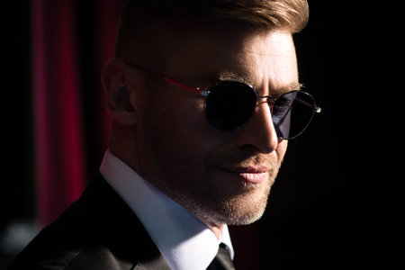 A close up dark portrait of a brutal handsome smiling man in sunglasses. Men's beauty, fashion....