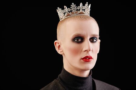 Portrait of a young man with womenâs makeup and with a crown on his head on a black background. Avant-garde fashion.の写真素材