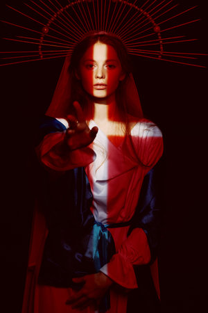 The Virgin Mary portrait on a dark background with rays of light. Modern art in religion.