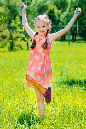 Happy little girl with pigtails in a summer park. Sunny day. Childhood. Kid's fashion.の写真素材