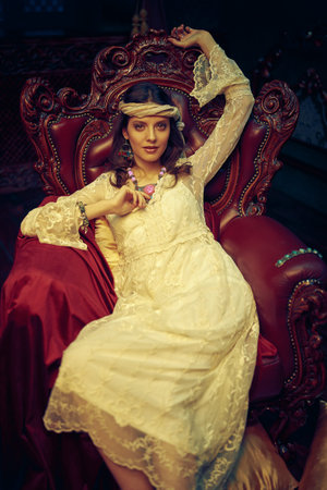 Bohemian lifestyle. Beautiful young woman in elegant lace dress and jewelry posing in a vintage...