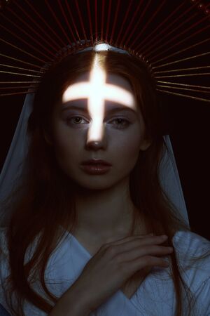 The Virgin Mary portrait on a dark background with a light in the form of a cross. Modern art in religion.の写真素材