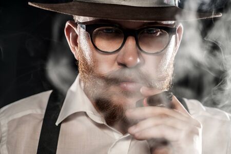 A close up portrait of a man smoking  a cigar. Men's beauty, fashion, style.の写真素材