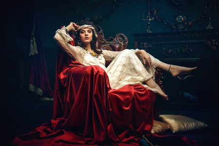 Bohemian lifestyle. Beautiful young woman in elegant lace dress and jewelry posing in a vintage...