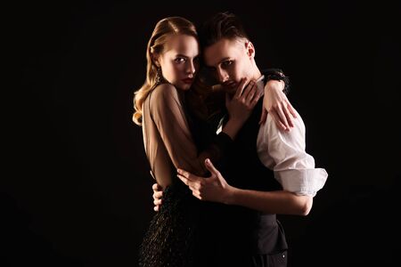 Beautiful passionate couple of man and woman in expensive evening dresses on a black background. Couple in love. Beauty, fashion.  Studio portrait.の写真素材