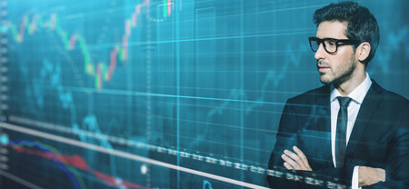 Portrait of a serious contemporary businessman looking at holographic charts. Business concept.