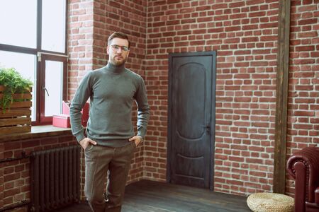 Handsome gentleman posing in casual clothes and glasses in a loft interior.  Men's beauty, fashion.の写真素材