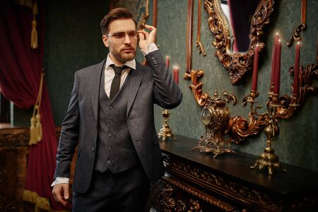 Handsome gentleman poses in a tweed suit and glasses in a vintage interior. Luxurious lifestyle. Vintage style.の写真素材