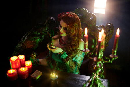 A beautiful red-haired fortune teller is talking to a black raven. The atmosphere of magic and...