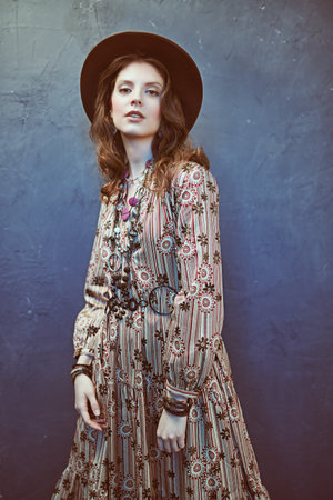 Fashion shot of a gorgeous young woman in boho style dress and accessories posing at studio....