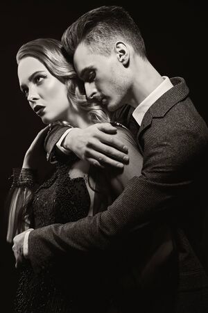 Beautiful passionate couple of man and woman in expensive evening dresses on a black background. Couple in love. Beauty, fashion.  Studio portrait.の写真素材