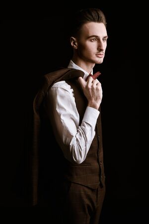 Portrait of a handsome man in elegant classic suit and bow tie on a black background. Business style. Men's fashion.の写真素材