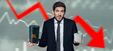 Coronavirus COVID-19 concept. A doubting businessman chooses between oil and toilet paper on a background of financial charts showing a falling economy.の写真素材