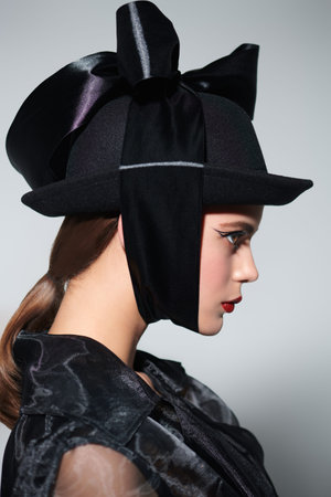 Hats fashion. Portrait of a charming young woman in a fashionable hat on a white background. Makeup...