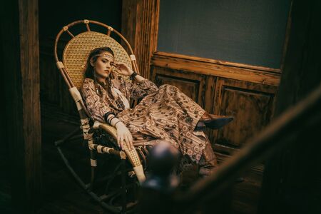 Bohemian lifestyle. Stunning young woman with hair, make-up and dress in boho style posing in a luxurious interior. Fashion shot.の写真素材