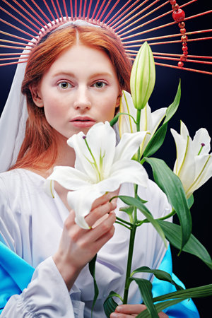 The Virgin Mary portrait with lilies on a dark background with rays of light. Modern art in religion.の写真素材