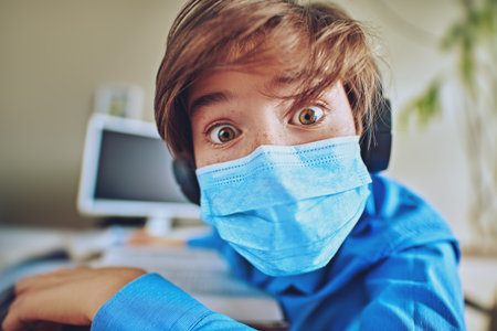 COVID-19 or coronavirus concept. A boy in a medical mask looks into the camera with big surprised...