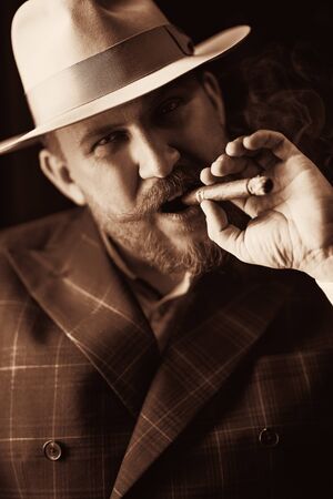 A portrait of a thoughtful man with a cigar posing in the vintage interior. Men's beauty, fashion, style.の写真素材
