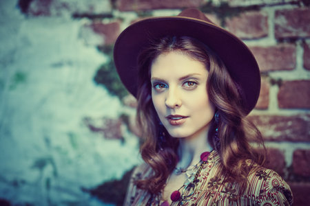 Portrait of a gorgeous young woman in boho style dress and accessories posing against the backdrop of the ruined walls, overgrown with moss. Bohemian, modern hippie style.の写真素材