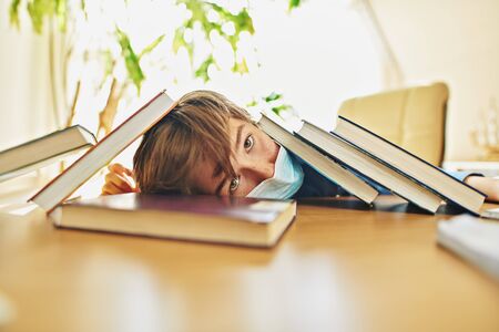Coronavirus and life. Boy schoolboy student in a medical mask stays home at distance learning due to quarantine because of COVID-19.の写真素材